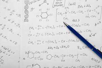 Sheets of paper with different chemical formulas and pen, top view