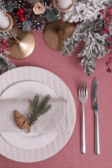 Festive place setting with beautiful dishware, cutlery and cone for Christmas dinner on pink tablecloth, flat lay
