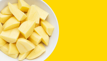 Raw peeled potatoes on yellow background