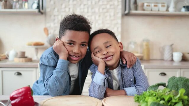 Cute african boys preparing for cooking healthy salad for first time. First lesson and healthy lifestyle concept. Healthy eating. Happy children boys preparing for eating vegetable salad in kitchen.