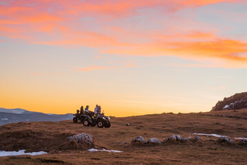 Group of friends riding quad bike atv off road on the mountain at sunset adventure travel. © Malik Nalik