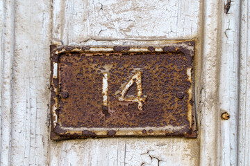 Old sign with the house number 14 on the background of the wall.
