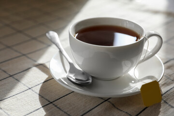 Bag of black tea in cup on table, closeup. Space for text