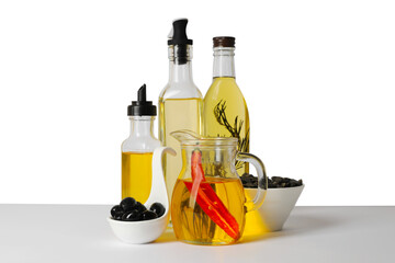 Bottles of different cooking oils, olives and sunflower seeds on white background