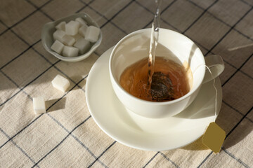 Pouring hot water into cup with tea bag on table, above view
