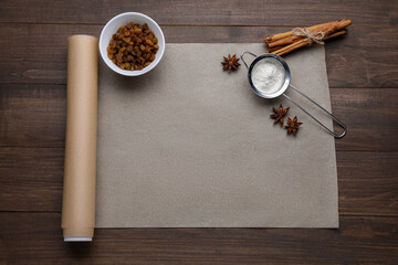 Baking parchment paper and different ingredients on wooden table, flat lay. Space for text