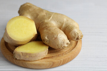 Cut and whole fresh ginger on white wooden table, closeup