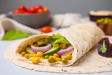 Delicious hummus wrap with vegetables on table, closeup