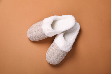 Pair of beautiful soft slippers on light brown background, top view