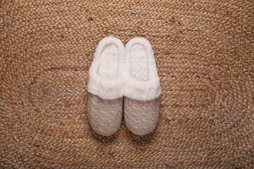 Fototapeta na wymiar Pair of beautiful soft slippers on wicker carpet, top view