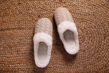 Fototapeta na wymiar Pair of warm stylish slippers on wicker carpet, top view