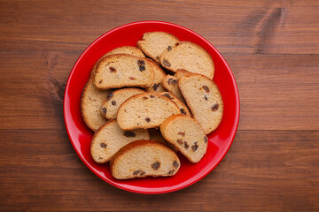 Plate of sweet hard chuck crackers with raisins on wooden table, top view