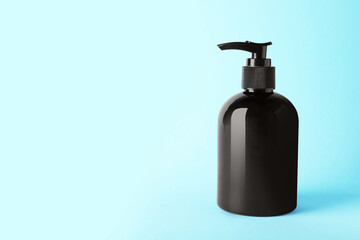Bottle of shampoo on light blue background, space for text