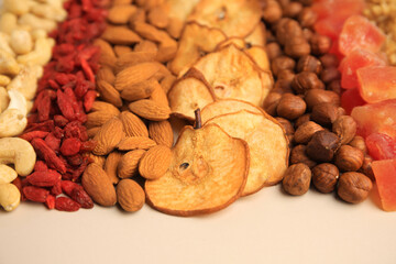 Mix of delicious dried nuts and fruits on beige background, closeup