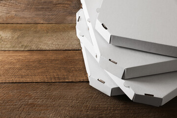 Stack of empty pizza boxes on wooden table, closeup. Space for text