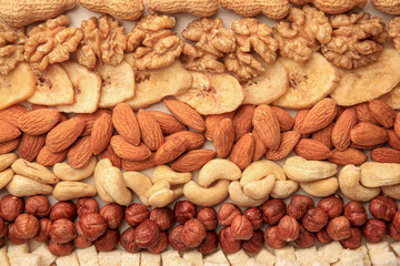 Different tasty nuts and dried fruits on beige background, flat lay
