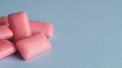 Heap of sweet chewing gums on light blue background, closeup. Space for text