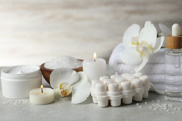 Fototapeta na wymiar Beautiful composition with different spa products, burning candles and flowers on light grey table