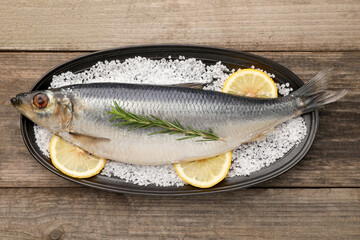 Plate with salted herring, rosemary and lemon on wooden table, top view