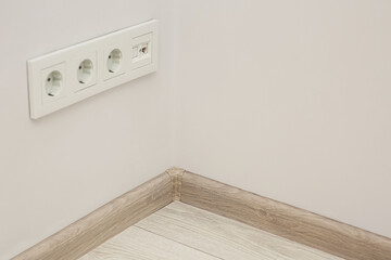 White wall with sockets and baseboard indoors, space for text