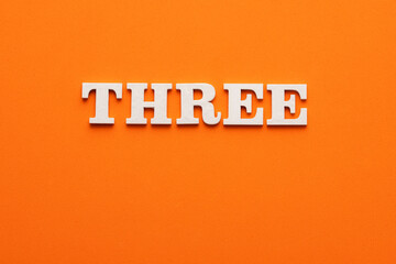 In white letters the word three on an orange background