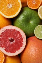 Different fresh whole and cut citrus fruits as background, top view