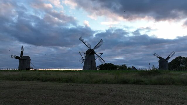 Landscape with windmills and a picup truck  passing in front of them. Angla village in Saaremaa, Estonia.