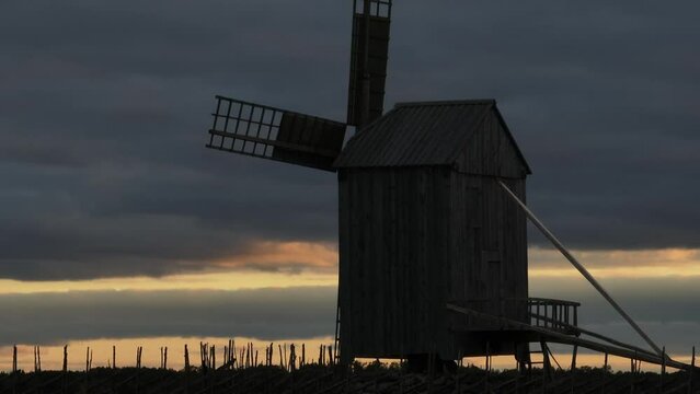 View of the windmill with birds flying past after sunset in Angla village in Saaremaa, Estonia.