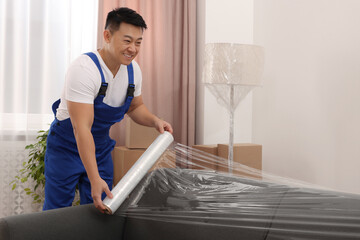 Worker wrapping sofa in stretch film indoors
