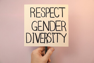 Woman holding sign with text Respect Gender Diversity on pink background, closeup