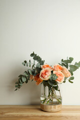 Bouquet with beautiful flowers in glass vase on wooden table against white background © New Africa