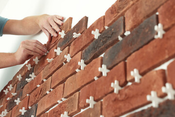 Professional builder gluing decorative brick on wall, closeup. Tiles installation process