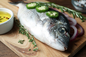 Fresh dorado fish and ingredients on wooden board, closeup