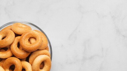 Bowl of tasty dry bagels (sushki) on white marble table, top view. Space for text