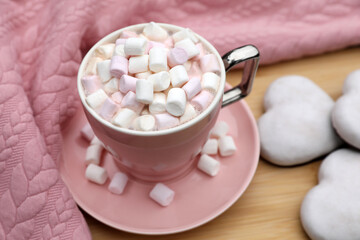 Obraz na płótnie Canvas Cup of tasty cocoa with marshmallows, pink sweater and cookies on wooden table