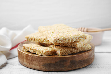 Wooden board with tasty sesame kozinaki bars on white table, closeup