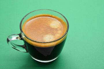 glass of black coffee put on green paper background