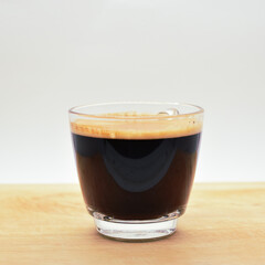 glass of black coffee put on wooden cutting board