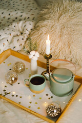 Hot tea, candle, Christmas golden balls and decorations. Christmas holiday mood in home. Winter concept.