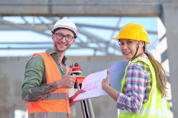 Two Construction Worker show success Using Theodolite Surveying Optical Instrument for Measuring Angles in Horizontal and Vertical Planes on Construction Site. Engineer and Architect Using blueprint