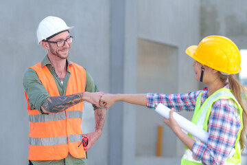 Two Construction Worker show success Using Theodolite Surveying Optical Instrument for Measuring Angles in Horizontal and Vertical Planes on Construction Site. Engineer and Architect Using blueprint