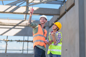 Two professionals inspect construction site of commercial building, industrial building, real estate project  civil engineer, investor using laplet in background crane, skyscraper, concrete formwork