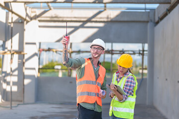 Two professionals inspect construction site of commercial building, industrial building, real estate project  civil engineer, investor using laplet in background crane, skyscraper, concrete formwork