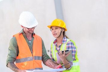 Two professionals inspect construction site of commercial building, industrial building, real estate project  civil engineer, investor using laplet in background crane, skyscraper, concrete formwork