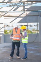 Two professionals inspect construction site of commercial building, industrial building, real estate project  civil engineer, investor using laplet in background crane, skyscraper, concrete formwork