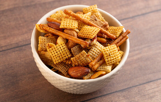 Bowl of Homemade Cereal Nut and Prezel Trail Mix on a Wooden Table