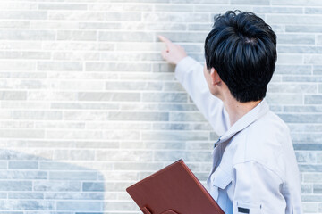 家の壁を点検する若い日本人男性