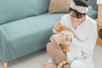 猫の爪切りをする飼い主のアジア人女性
