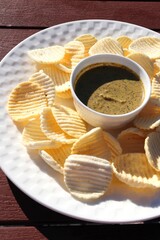 Freshly Fried sago and Potato chips in a wooden basket with dip sauce on a table. Close-up top view. Potato Wafers snacks. copy space. Fast food.