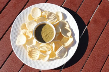 Freshly Fried sago and Potato chips in a wooden basket with dip sauce on a table. Close-up top view. Potato Wafers snacks. copy space. Fast food.